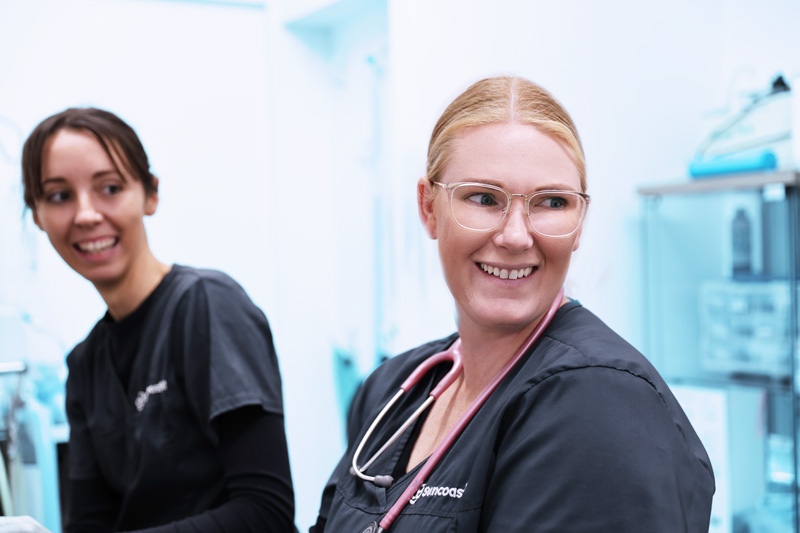 Two smiling female SuncoastVet staff members with stethoscope in treatment area